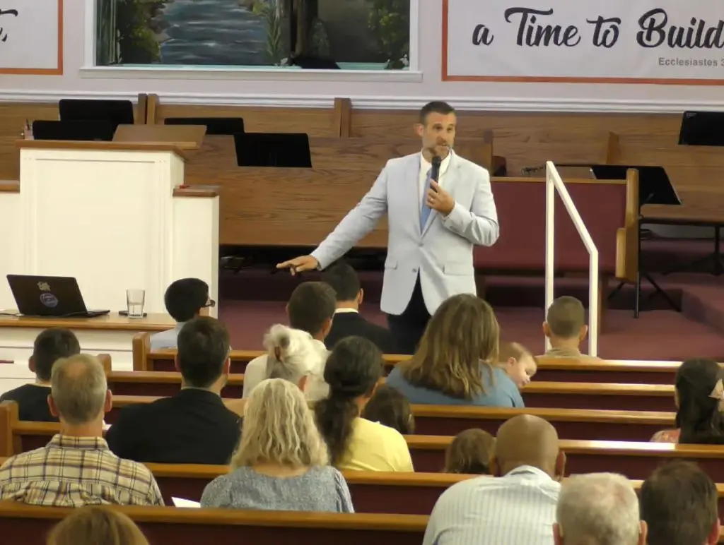 Pastor Adam Fannin preaching to families in the pews