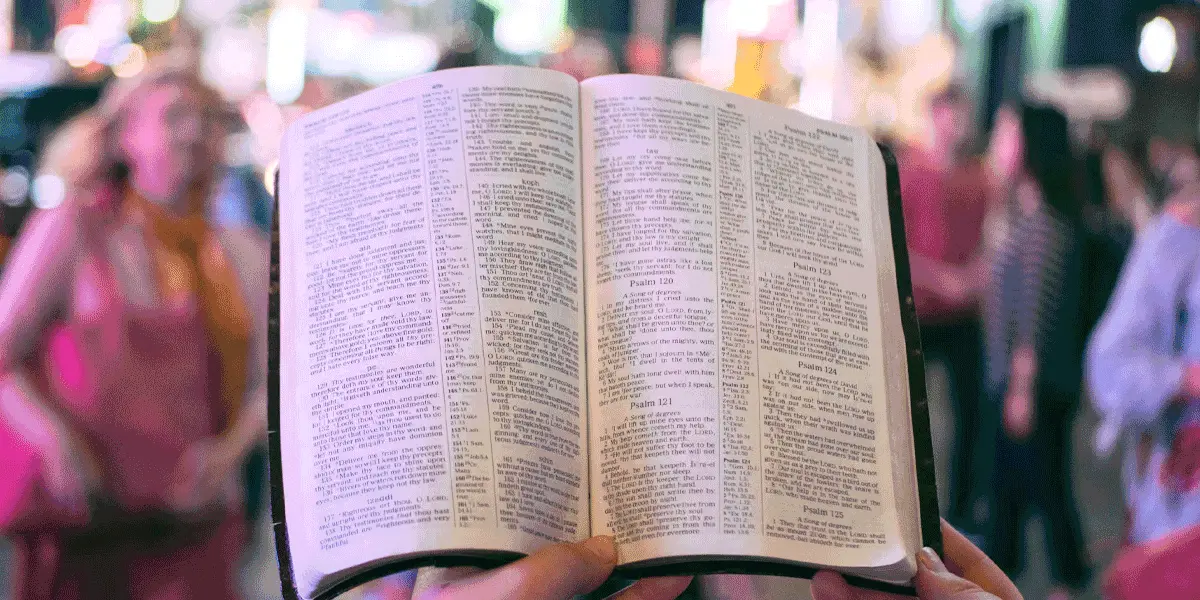 An open King James Bible held up on a busy street